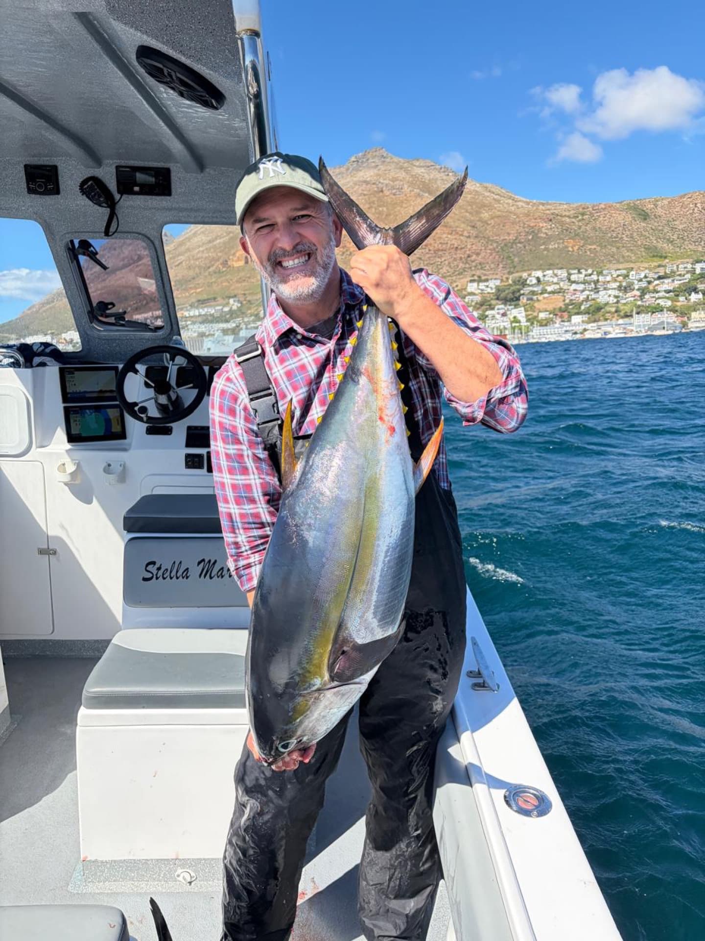An angler holding a yellowfin tuna on the deck of the Stella Maria
