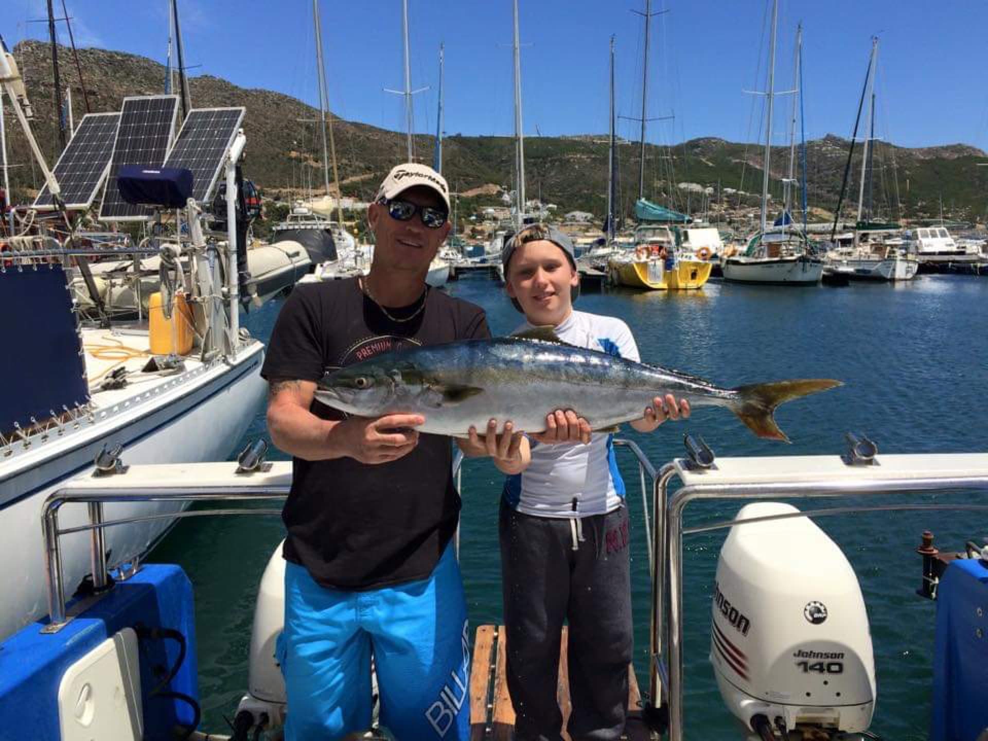 A father and son holding a yellowtail caught in False Bay